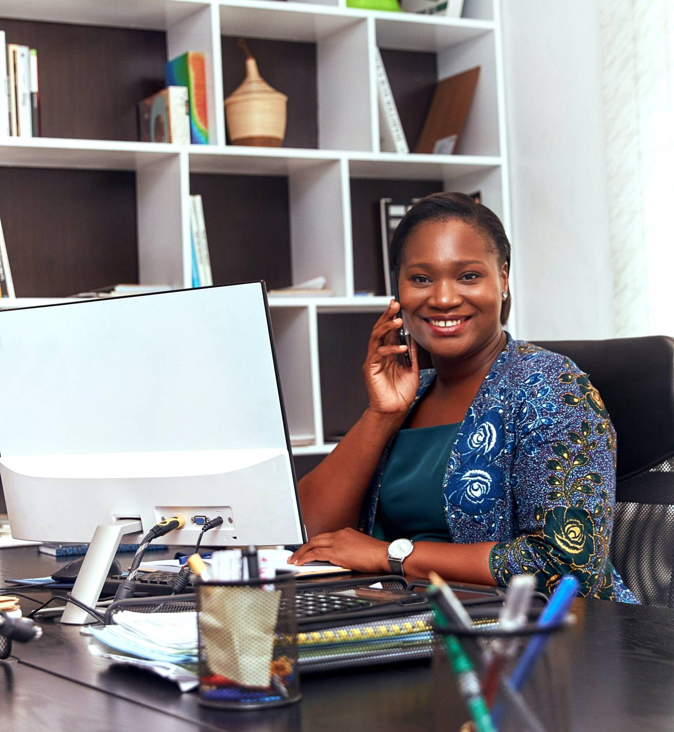 A lady smiling in her office and looking at the camera